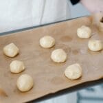 Blacha z kulkami ciasta trzymana w dłoniach przed pieczeniem