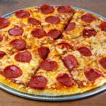 Chrupiąca pizza pepperoni z serem na drewnianym, rustykalnym stole