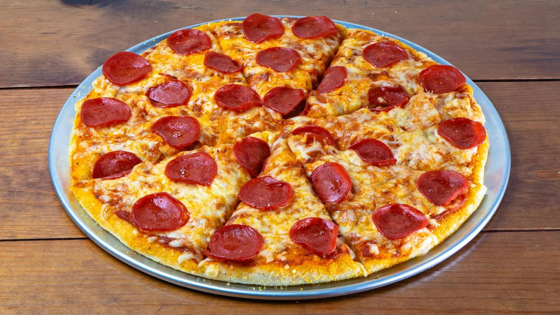 Chrupiąca pizza pepperoni z serem na drewnianym, rustykalnym stole