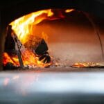 Pizza pieczona w tradycyjnym piecu opalanym drewnem z widocznym płomieniem