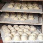 Surowe bochenki chleba dojrzewające na półkach w piekarni