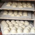 Surowe bochenki chleba dojrzewające na półkach w piekarni