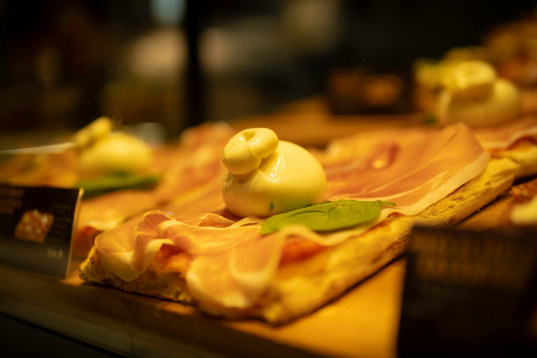 Zbliżenie na pizzę bianca z burratą, prosciutto i listkami bazylii