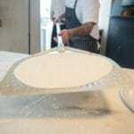 Pizzaiolo porcjuje ciasto na pizze w profesjonalnej kuchni