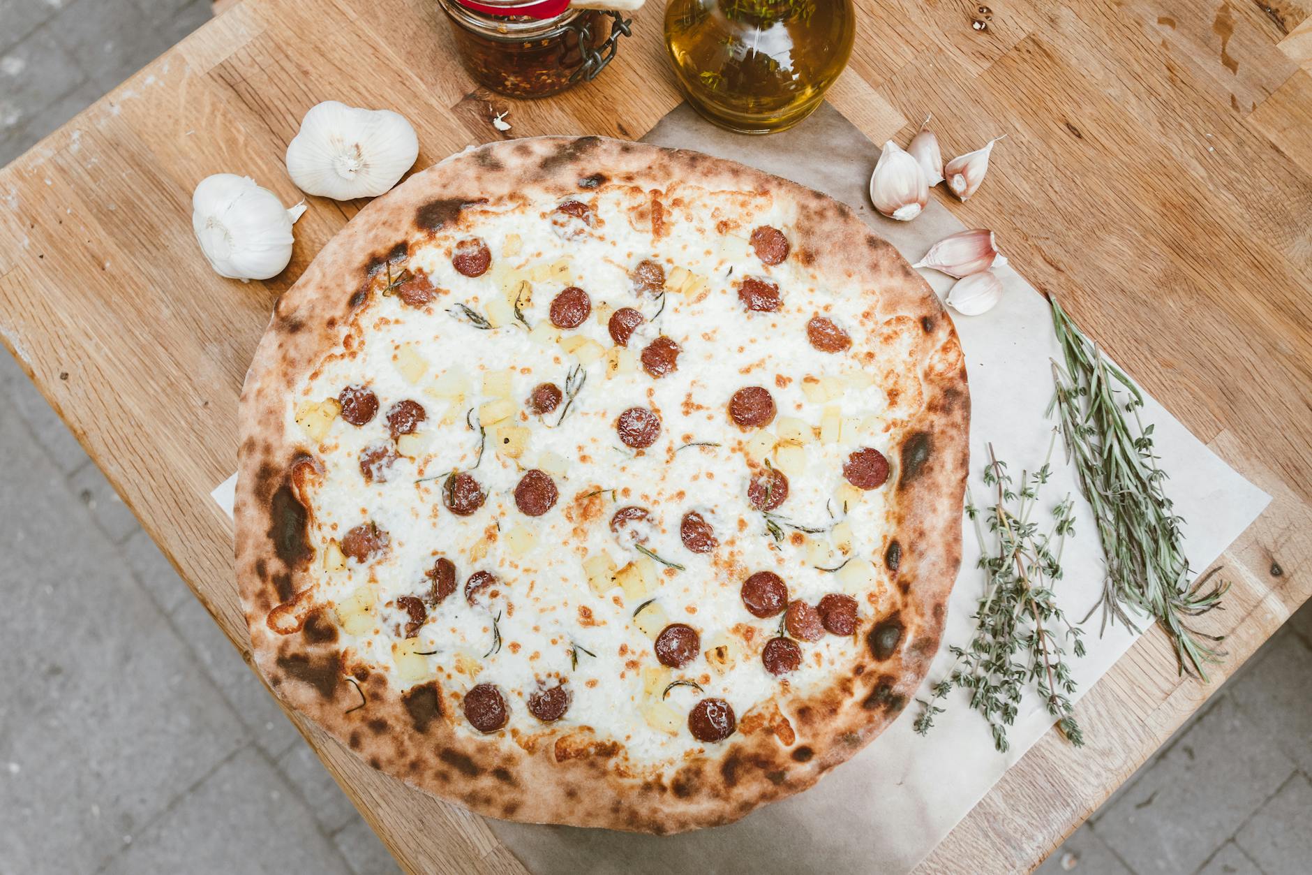 Pizza pepperoni na drewnianym stole z ząbkami świeżego czosnku