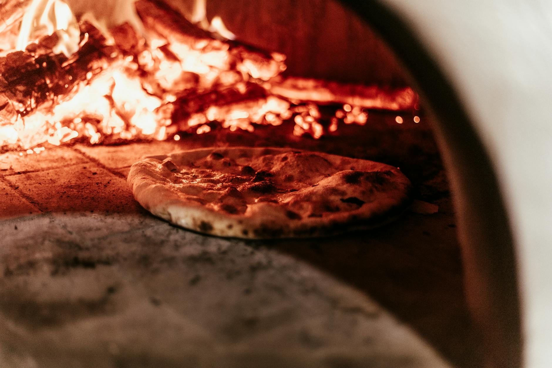 Pizza piecząca się w tradycyjnym piecu opalanym drewnem