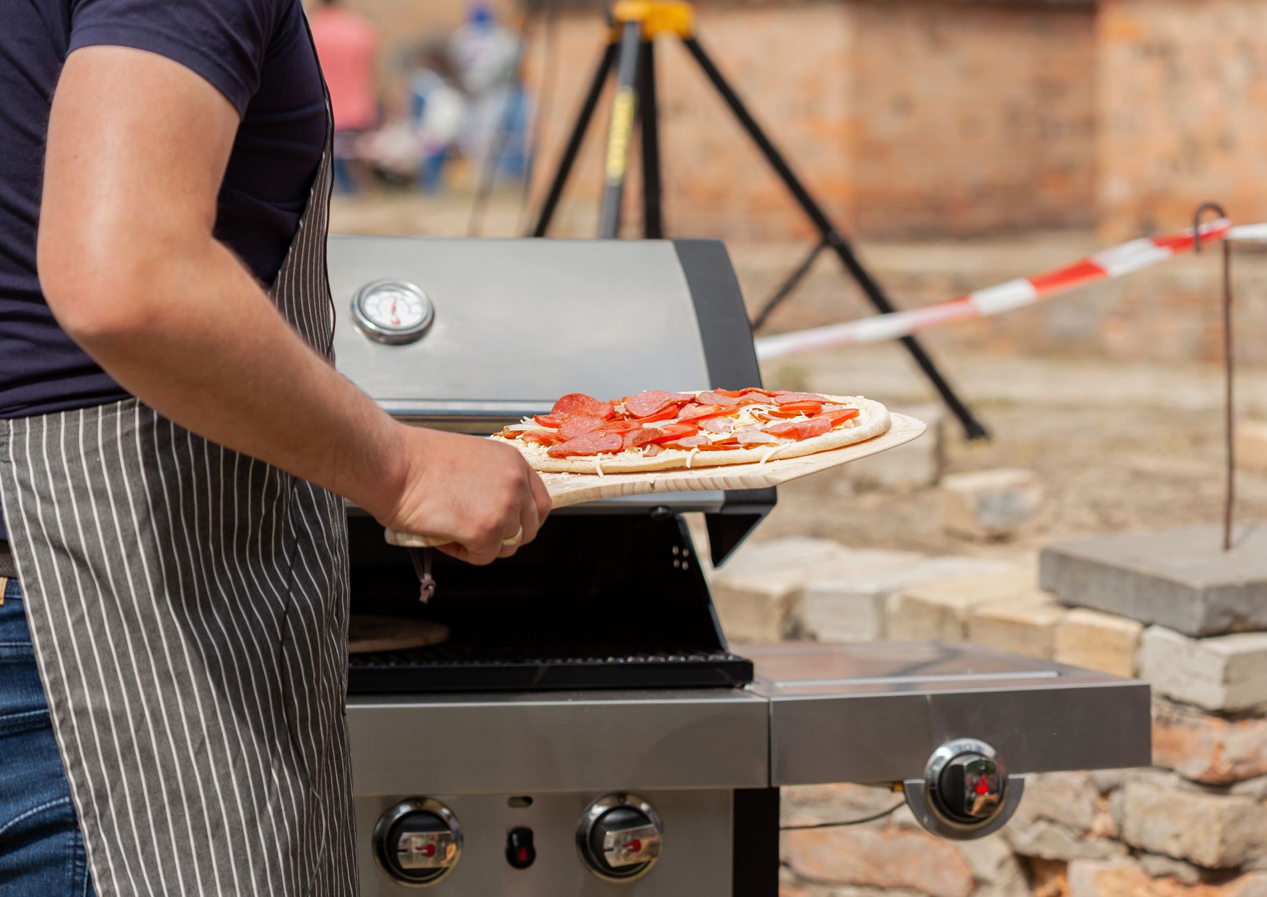 Piec do pizzy na pellet: wygoda, smak i temperatura w porównaniu do gazu Mężczyzna piecze pepperoni pizzę na zewnętrznym grillu