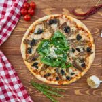 Włoska pizza z zieleniną na drewnianym stole z czerwoną serwetką