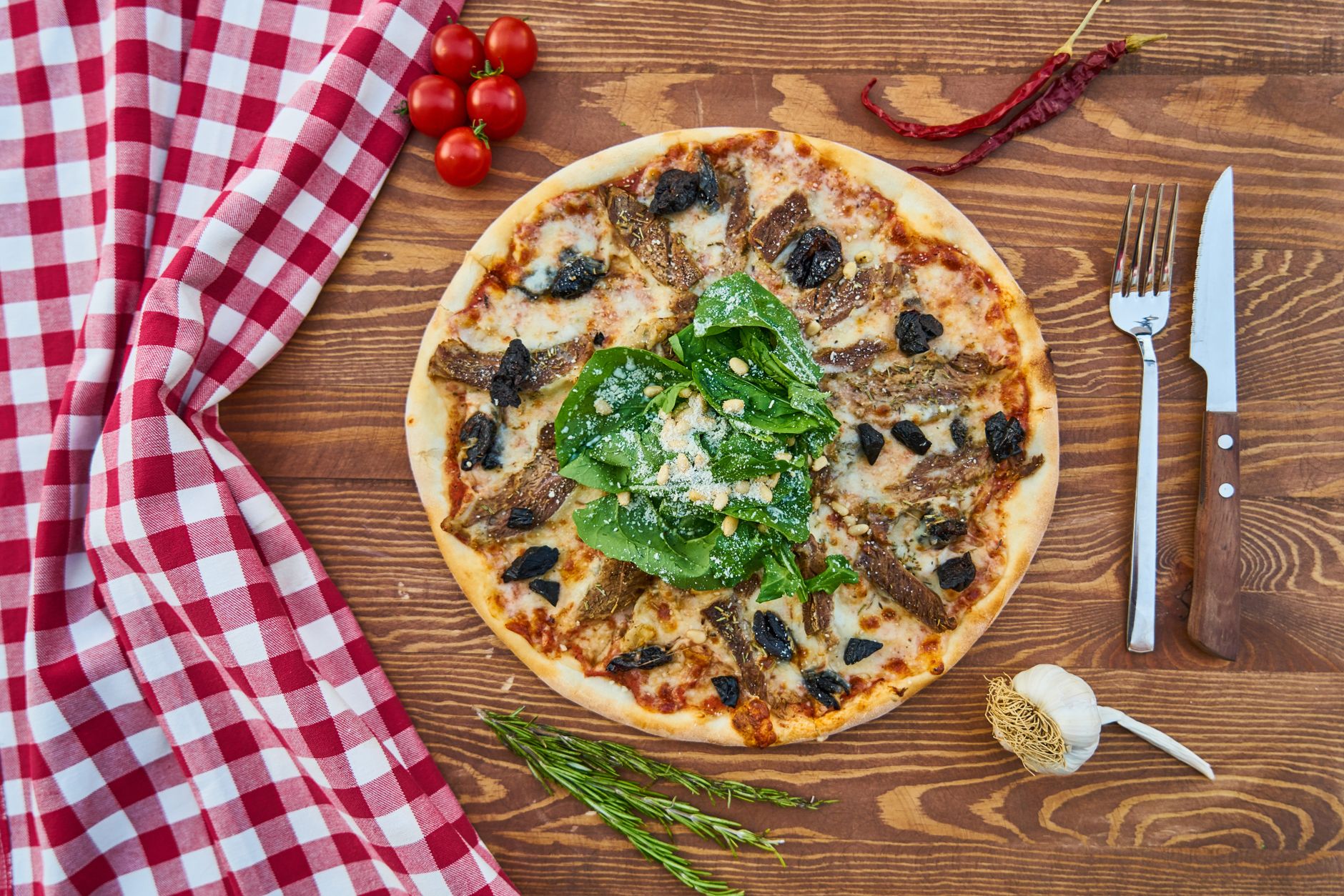 Włoska pizza z zieleniną na drewnianym stole z czerwoną serwetką